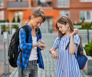 pupil-friends-boy-girl-playing-smart-watch-near-school_496169-161